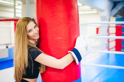 Young woman exercising in the gym. Woman hugging a punching bag