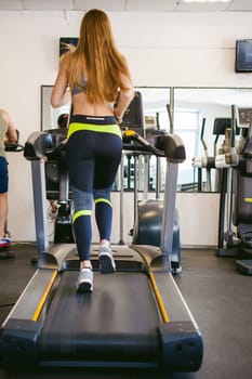 Active young woman running on treadmill at the gym exercising. Run on a machine.