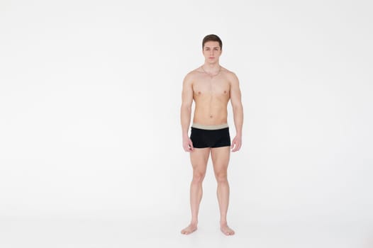 studio portrait young sexy men bodybuilder athlete, with a bare torso, Standing in full length on a white background in underwear underwear, Belt is photographed, gold chain with a cross on the neck