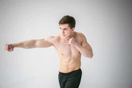 young sexy handsome men of strong Athlete's body with bare torso, Dressed black sports shorts, portrait of studio of light-skinned strong man standing in fighting stance, straining powerful hands