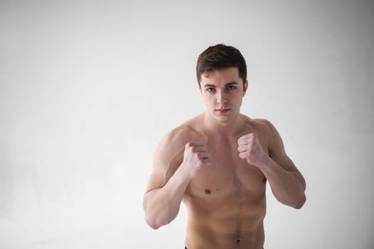 young sexy handsome men of strong Athlete's body with bare torso, Dressed black sports shorts, portrait of studio of light-skinned strong man standing in fighting stance, straining powerful hands