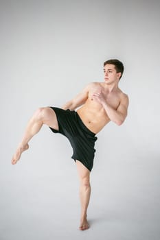 young sexy handsome men strong Athlete's body with bare torso, Dressed black sports shorts, portrait of studio of light-skinned strong man standing in fighting stance Kicking, straining powerful legs