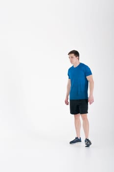 Young muscular handsome athletic man dressed in blue sport shirt, shorts and sneakers standing on white background in studio, Taking a step