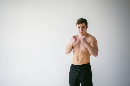 young sexy handsome men of strong Athlete's body with bare torso, Dressed black sports shorts, portrait of studio of light-skinned strong man standing in fighting stance, straining powerful hands