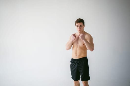young sexy handsome men of strong Athlete's body with bare torso, Dressed black sports shorts, portrait of studio of light-skinned strong man standing in fighting stance, straining powerful hands