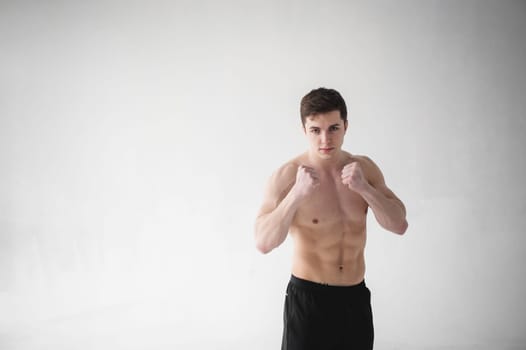 young sexy handsome men of strong Athlete's body with bare torso, Dressed black sports shorts, portrait of studio of light-skinned strong man standing in fighting stance, straining powerful hands