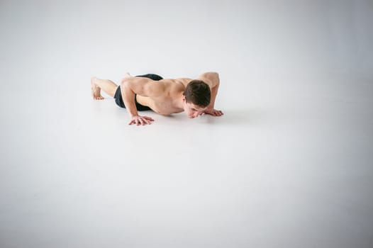 young sexy handsome men of strong Athlete's body with bare torso, Dressed black sports shorts, portrait of studio of light-skinned strong man engaged in push-ups, on floor, straining powerful hands
