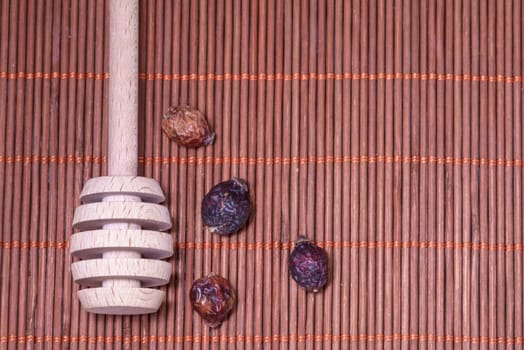 Dry Rosehip fruit for healty tisane and spoon for honey on a nice wicker carpet as background