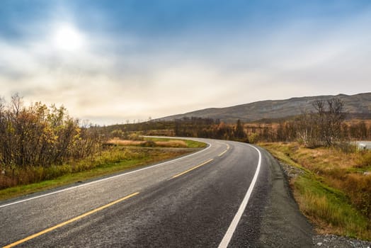 Asphalt sharp curved road along the forest and mountain, Tromso, Norway