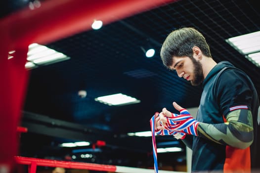 Professional Muay Thai and K1 fighter. Male boxer in training sportswear, an exercise in the sports hall, Preparation Boxing bandage