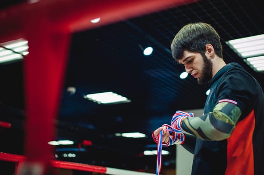 Professional Muay Thai and K1 fighter. Male boxer in training sportswear, an exercise in the sports hall, Preparation Boxing bandage
