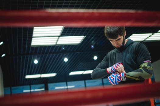 Professional Muay Thai and K1 fighter. Male boxer in training sportswear, an exercise in the sports hall, Preparation Boxing bandage