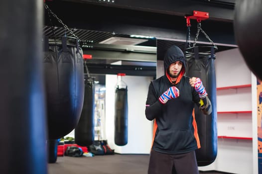 Professional Muay Thai fighter. Male boxer in training sportswear, an exercise in sports hall, fight with a shadow, Strike testing