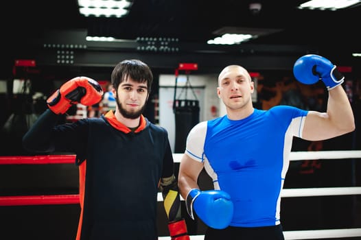 Professional Muay Thai fighter. Male boxer in training sportswear, an exercise in sports hall, fight with a shadow in ring, Strike testing Sparring partner