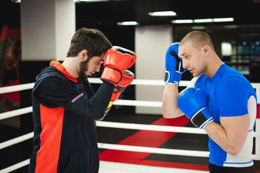 Professional Muay Thai fighter. Male boxer in training sportswear, an exercise in sports hall, fight with a shadow in ring, Strike testing Sparring partner