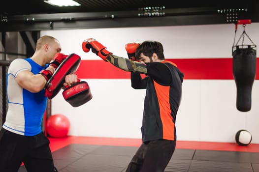 Two professionals fighters training together with punching pads at gym