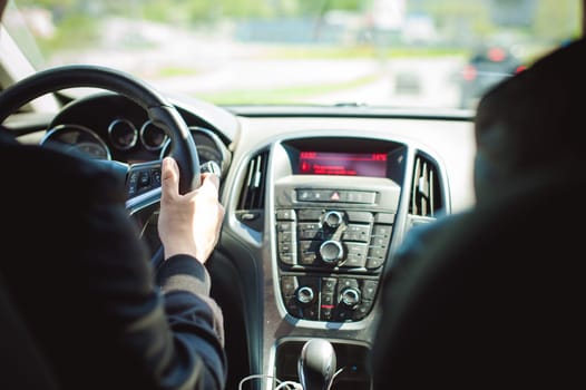 young bearded man driving a car, inside cabin rides, looking at road, driving, holding steering wheel.