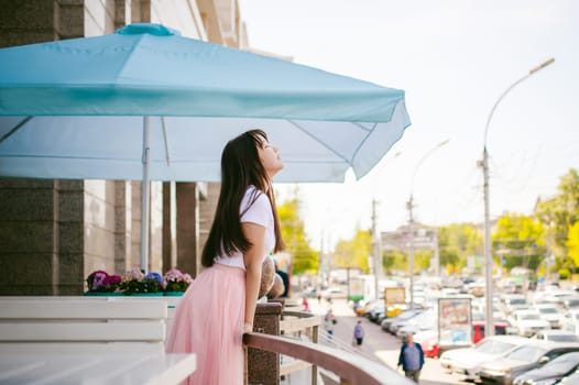 Cute asian young woman in summer cafe outdoors. girl In white T-shirt, with long hair in simple light cozy interior of restaurant Urban style