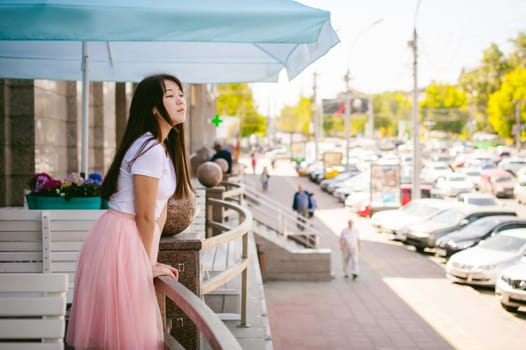 Cute asian young woman in summer cafe outdoors. girl In white T-shirt, with long hair in simple light cozy interior of restaurant Urban style