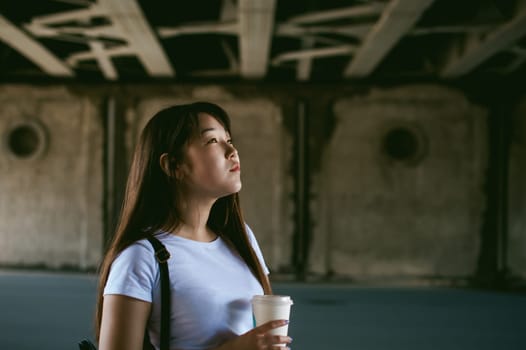 Cute asian young woman with a glass of takeaway, walks in an urban environment