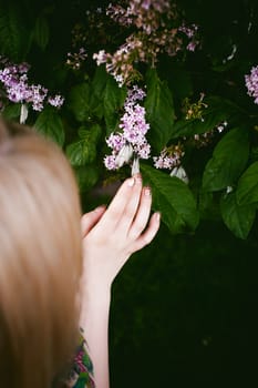 female fingers hold white butterflies on flowers of lilac and green leaves