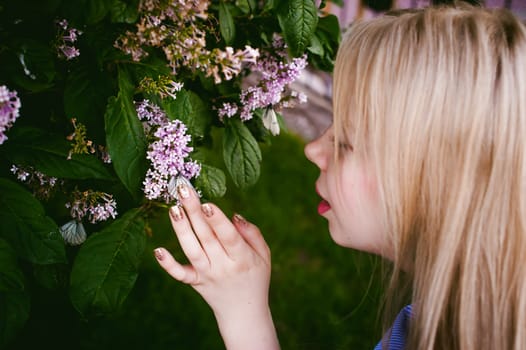 female fingers hold white butterflies on flowers of lilac and green leaves