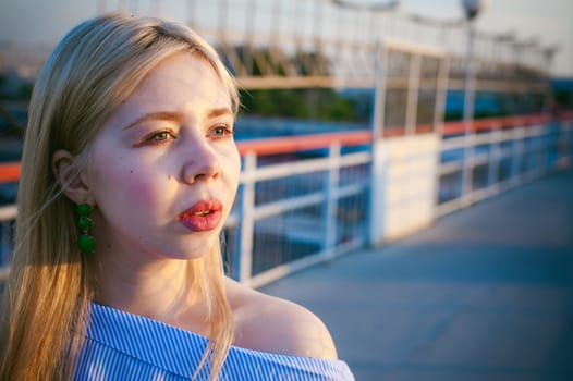 portrait of a cute young blond woman in a summer day against the background of a railway station