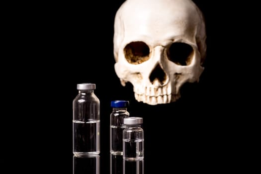 medical vials and blurry skull isolated on black background