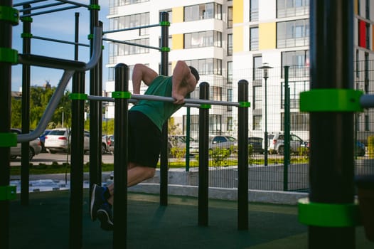 Handsome sexy male bodybuilder athlete man doing crossfit workout in athletic facilities on sunny morning outdoors. Healthy lifestyle concept. Physical preparation of the body