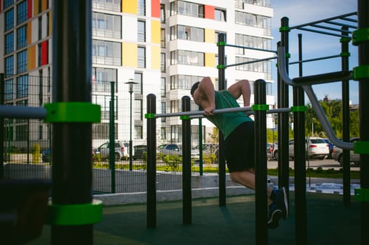 Handsome sexy male bodybuilder athlete man doing crossfit workout in athletic facilities on sunny morning outdoors. Healthy lifestyle concept. Physical preparation of the body