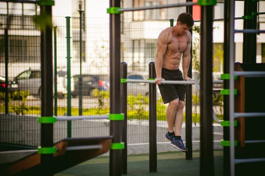 Handsome sexy male bodybuilder athlete man doing crossfit workout in athletic facilities on sunny morning outdoors. Healthy lifestyle concept.