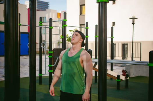 Handsome sexy male bodybuilder athlete man doing crossfit workout in athletic facilities on sunny morning outdoors. Healthy lifestyle concept. Physical preparation of body. pull-up on horizontal bar