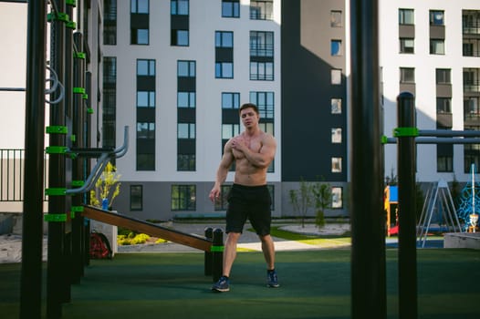 Handsome sexy male bodybuilder athlete man doing crossfit workout in athletic facilities on sunny morning outdoors. Healthy lifestyle concept.