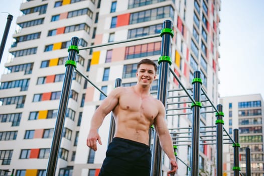 Handsome sexy male bodybuilder athlete man doing crossfit workout in athletic facilities on sunny morning outdoors. Healthy lifestyle concept. Physical preparation of body. Model poses showing muscles