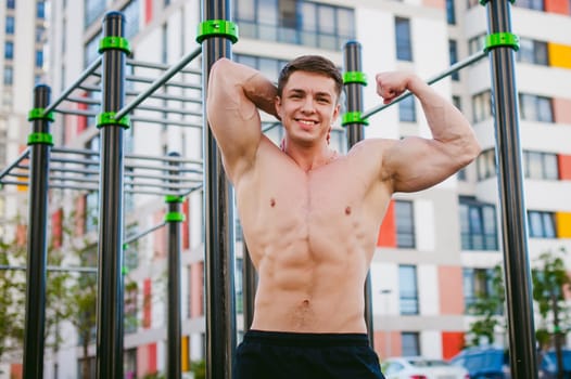 Handsome sexy male bodybuilder athlete man doing crossfit workout in athletic facilities on sunny morning outdoors. Healthy lifestyle concept. Physical preparation of body. Model poses showing muscles