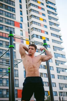 Handsome sexy male bodybuilder athlete man doing crossfit workout in athletic facilities on sunny morning outdoors. Healthy lifestyle concept. Physical preparation of body. Model poses showing muscles