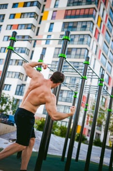 Handsome sexy male bodybuilder athlete man doing crossfit workout in athletic facilities on sunny morning outdoors. Healthy lifestyle concept. Physical preparation of body. Model poses showing muscles