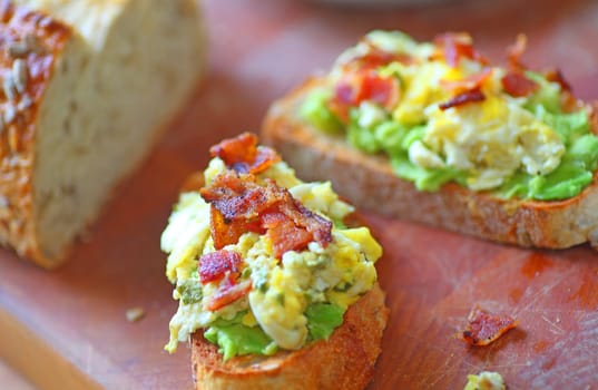 Toasted whole grain bread with avocado, scrambled eggs and bacon