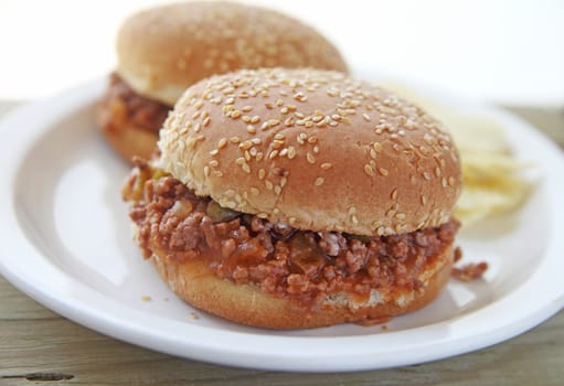 Two sloppy joe sandwiches on sesame seed buns with potato chips and room for text