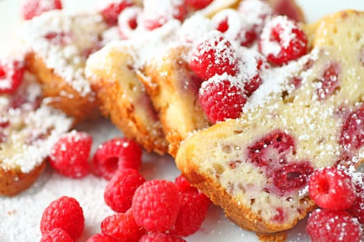 Slices of raspberry loaf cake with powdered sugar and fresh berries closeup