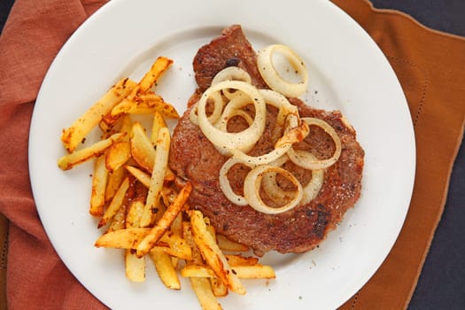 Ribeye steak with french fries and onions