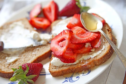 Fresh strawberries and cream cheese on wheat bread with honey
