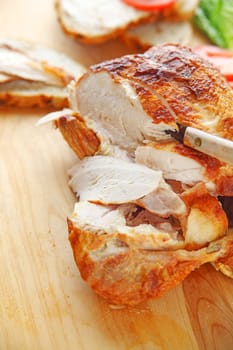 a purchased rotisserie roast chicken with knife on cutting board with room for text