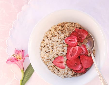 Bowl of raw oatmeal and died berries with flower and copy space