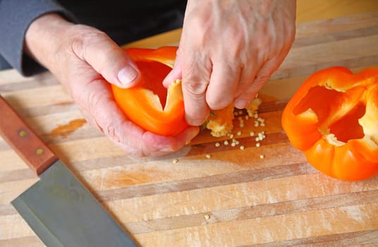 A man removes seeds from an orange bell pepper with room for text