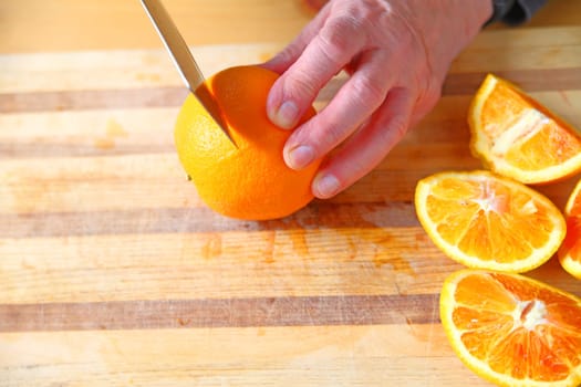 A man cuts up blood oranges on a cutting board with room for text