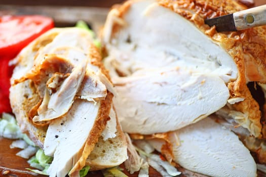 Sandwich made from a store-bought roast chicken with tomato slices and knife