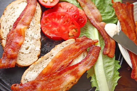 All the items needed to make a bacon, lettuce and tomato sandwich on onion rye bread
