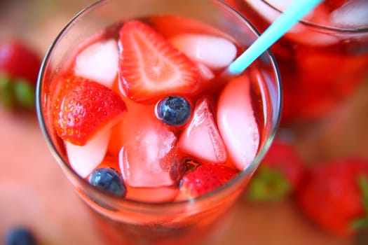 Overhead view of a healthy drink of water, blueberries, strawberries and ice