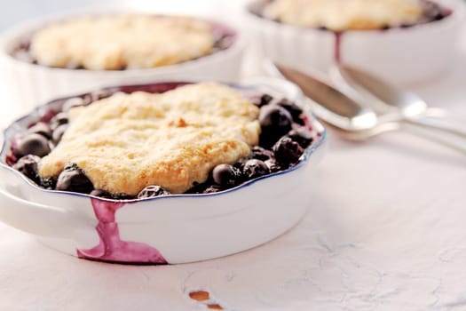 blueberry cobblers, desserts, blueberries, fresh fruit, homemade food, home cooking, white napkin, closeup, spoons, copy space, room for text, sweet, baked, natural light, textures, studio shot, indoors, no people.